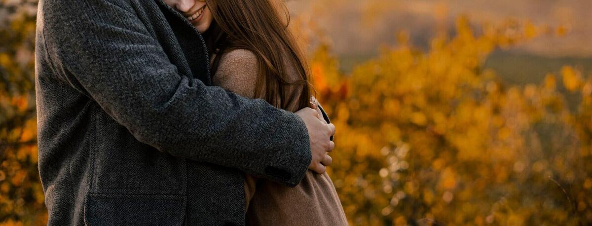 Close-up woman being hugged by man