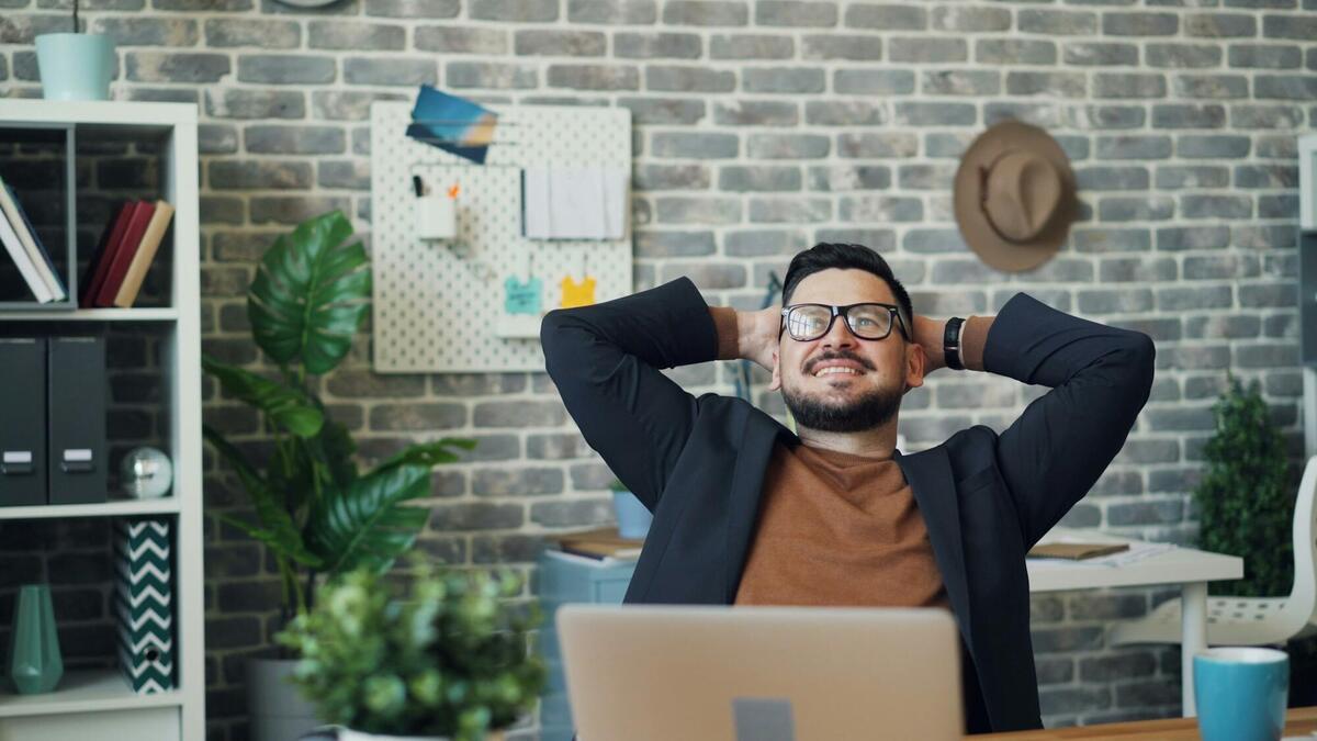 a man sitting at a desk with his hands behind his head