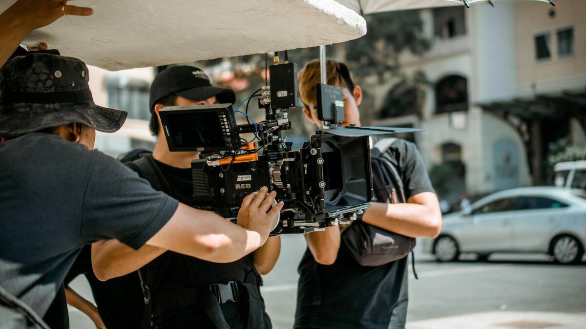 A film crew operates a RED camera on a city street, capturing a professional scene.