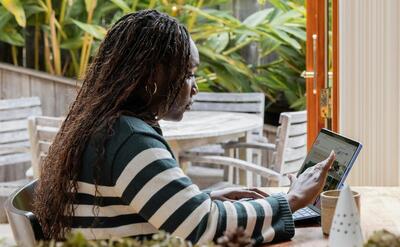 a person standing in front of a laptop computer talking on a cell phone