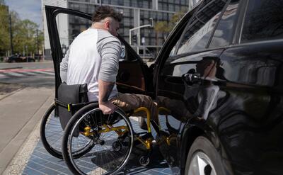 Full shot man in wheelchair near car