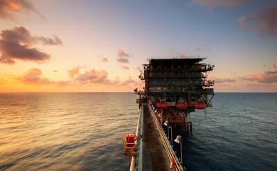 A breathtaking view of an oil platform on the ocean at sunset, showcasing industrial beauty.