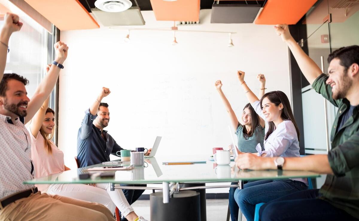 Ambitious workers keeping hands up to show their positive mood in break time in meeting room