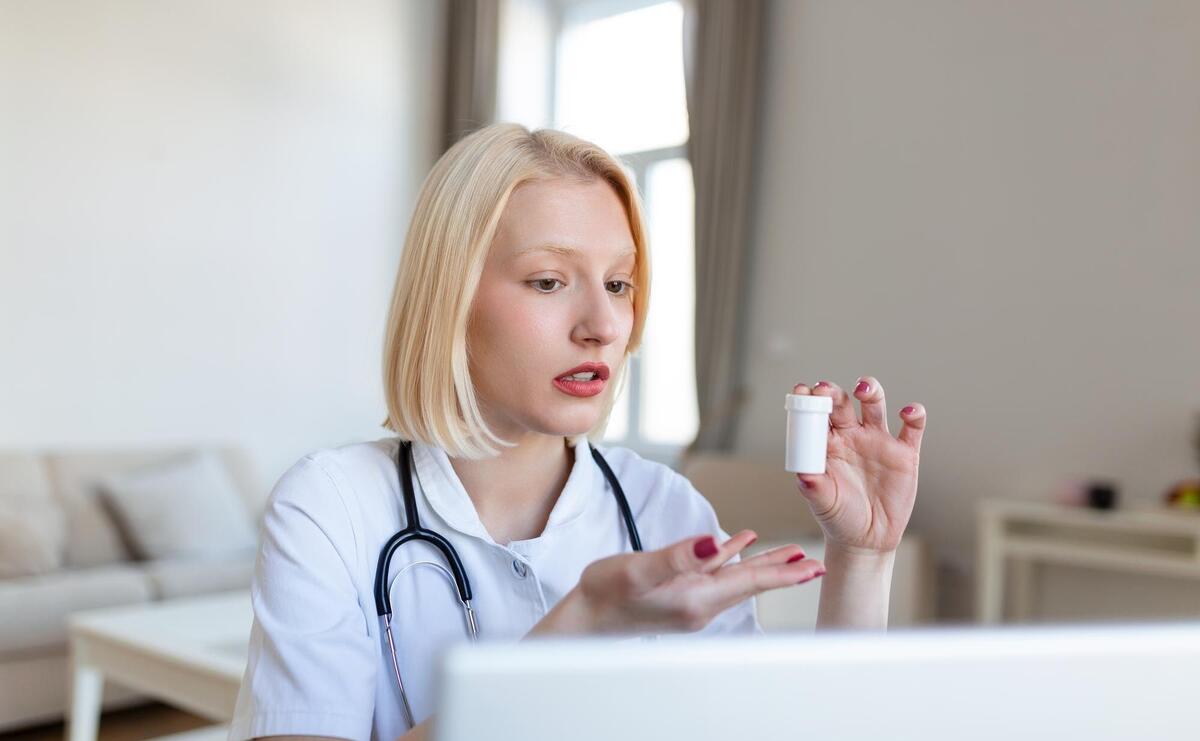 Female doctor talking while explaining medical treatment to patient through a video call with laptop in the consultation