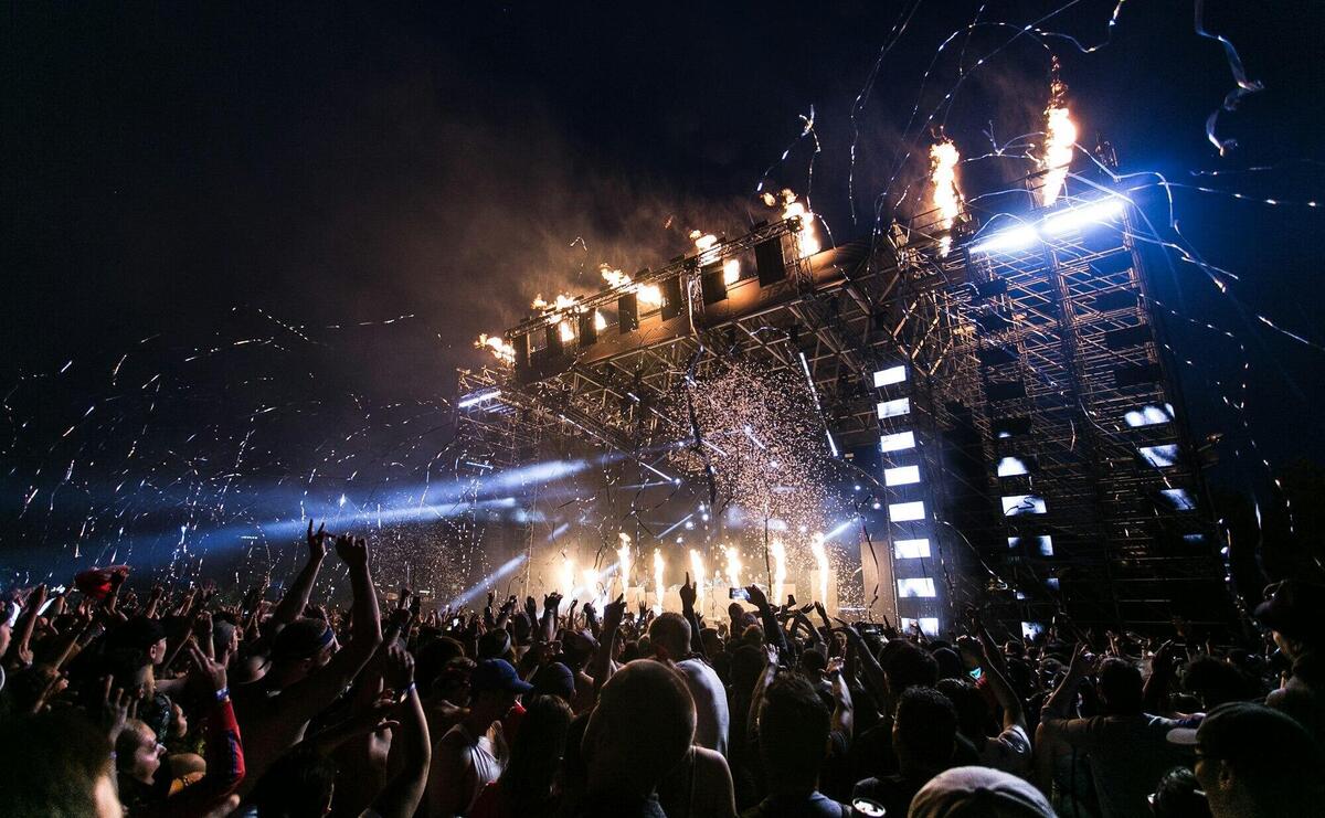 Vibrant concert scene with crowd enjoying night festival and dynamic stage fireworks.