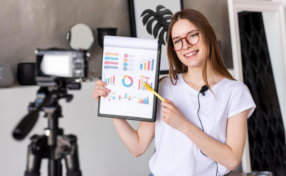 Young blogger recording with professional camera holding clipboard with graphics