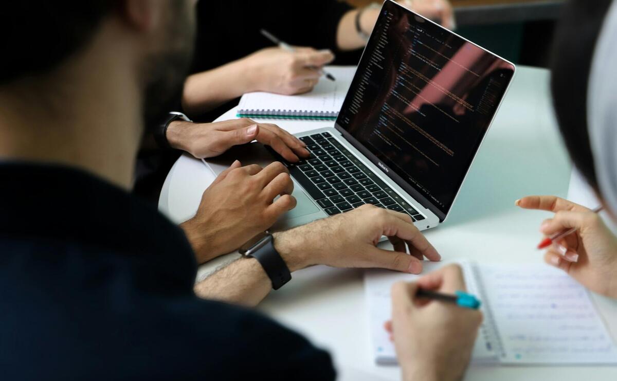 a group of people sitting around a laptop computer