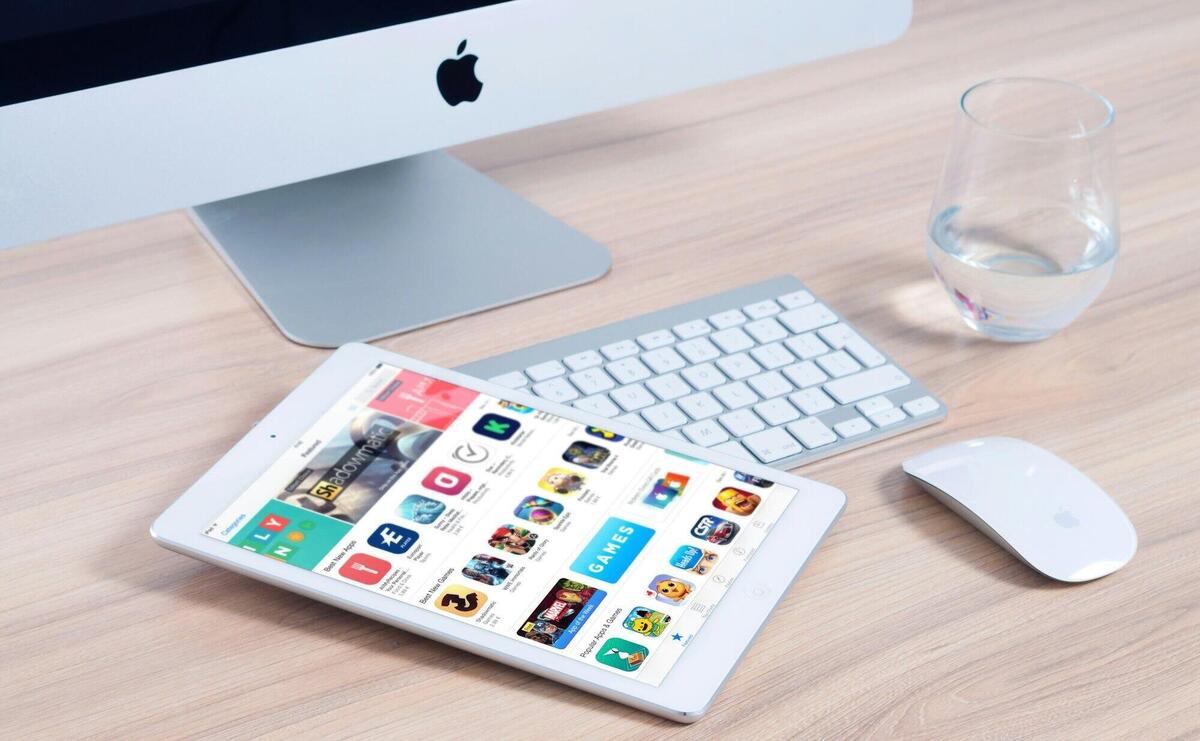 Sleek home office setup featuring an iMac and iPad showcasing apps.