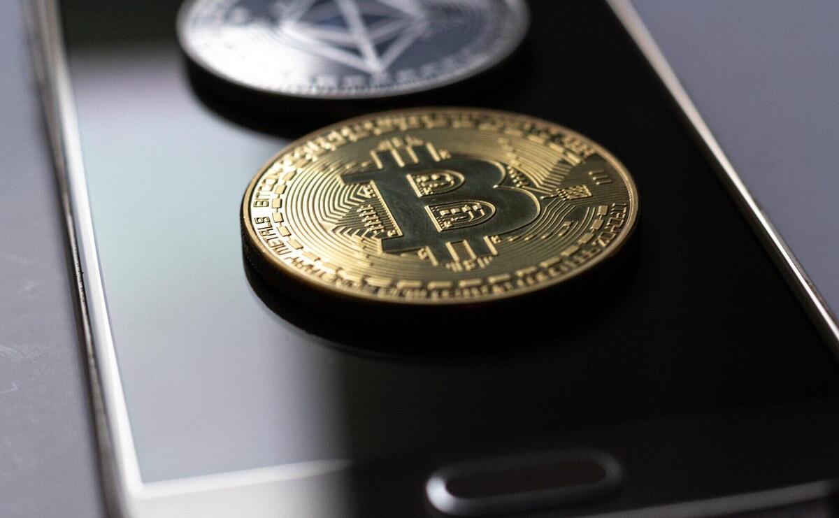 Closeup shot of two coins placed on top of a mobile phone