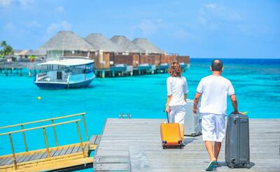 A couple arriving at a luxurious Maldives resort dock with luggage, capturing a tropical vacation vibe.