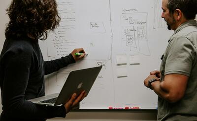 man wearing gray polo shirt beside dry-erase board