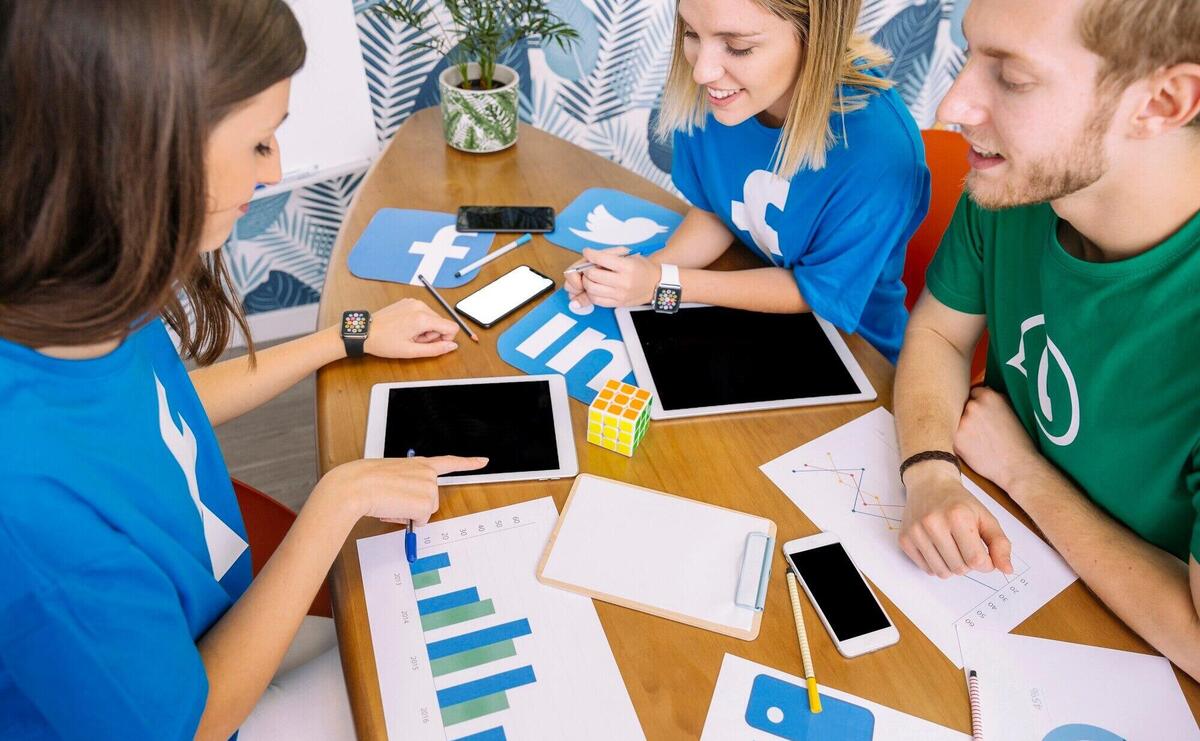 Group of people looking at digital tablet with social media icons at workplace