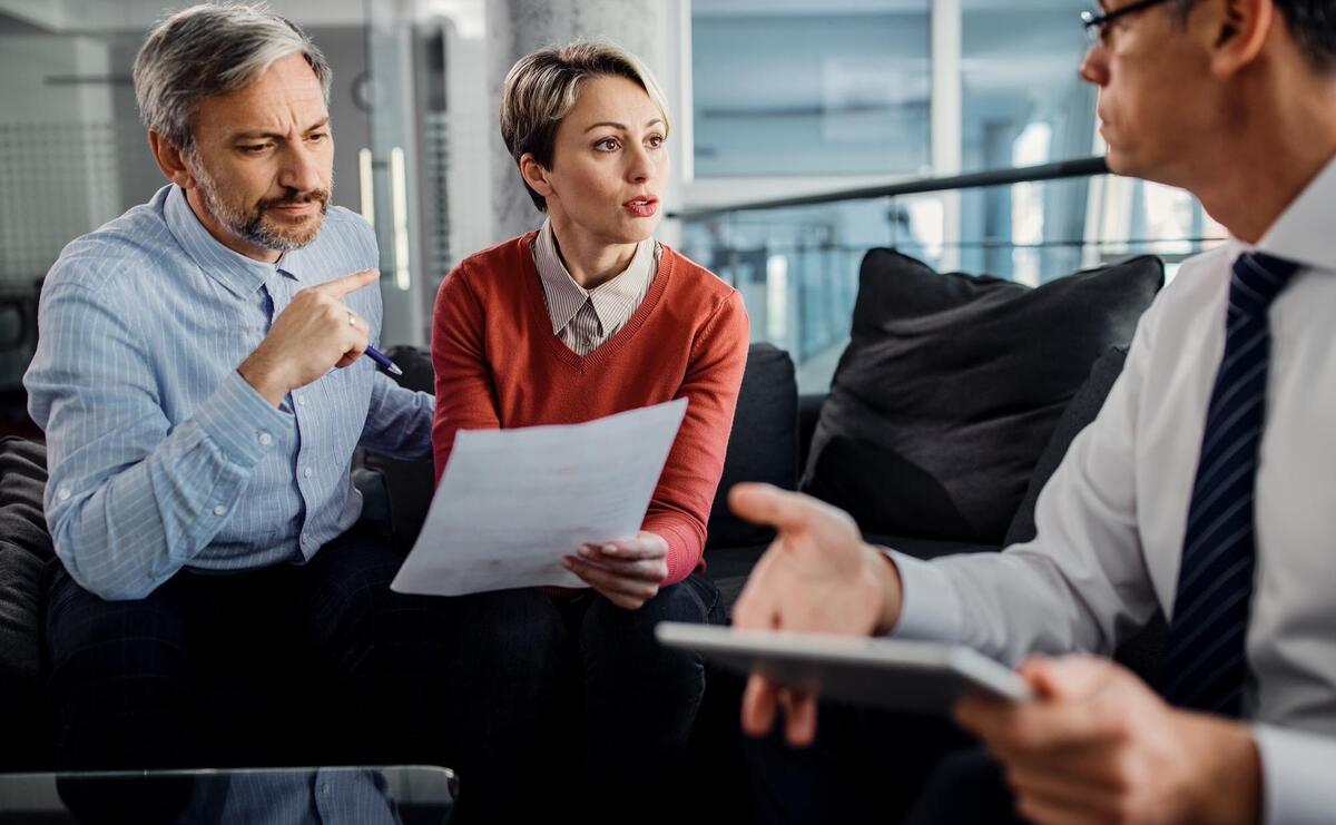 Mid adult couple and their financial advisor discussing about paperwork during the meeting