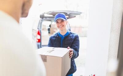 Cheerful courier giving package to client