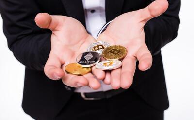 Man holds different crypto coins in his hands on white