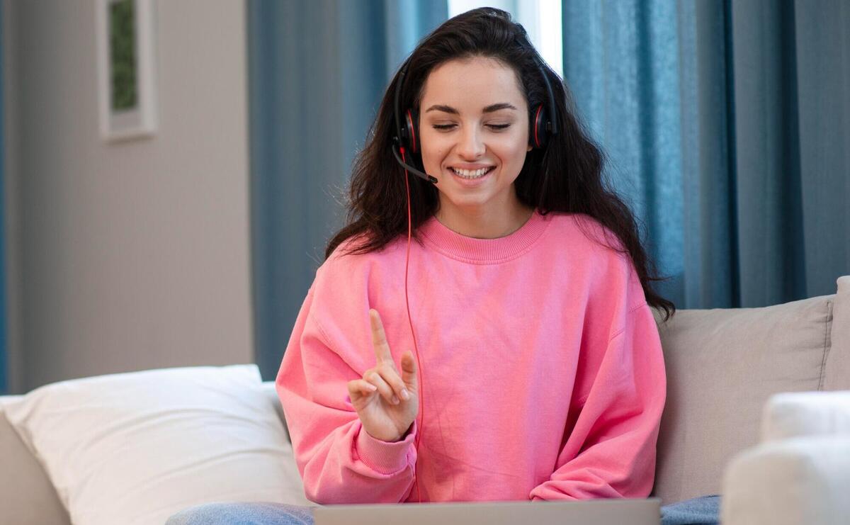 Woman in pink blouse with headset pointing up.