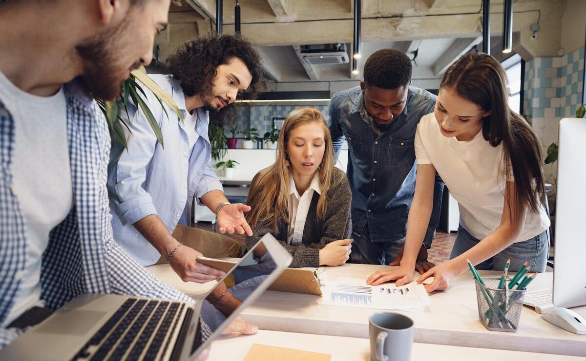 Team of diverse coworkers in modern office discuss their project together