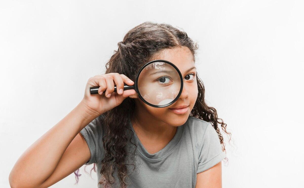 Close-up of a girl looking through magnifying glass