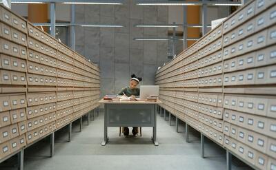 A Girl Writing on a Desk Between Card Catalogs