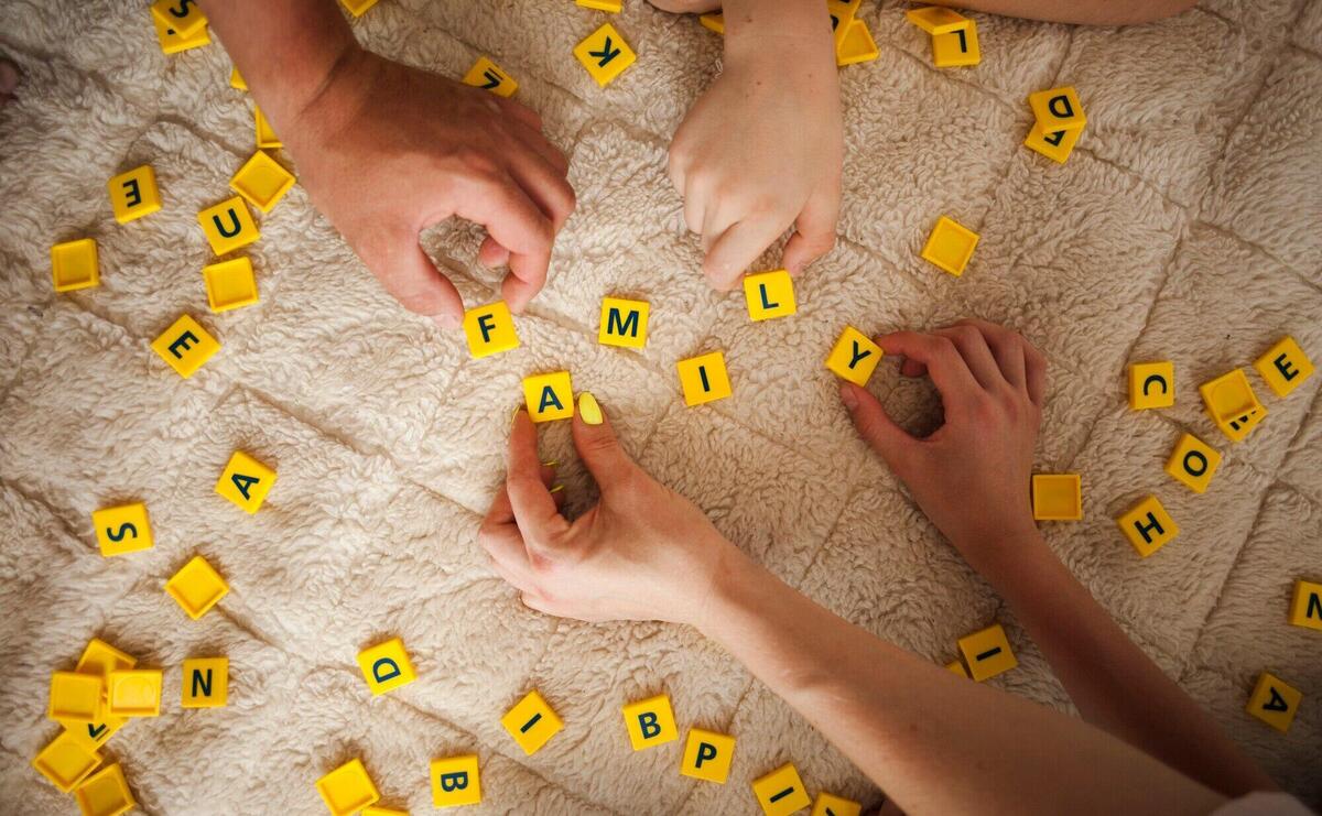 Hands playing scrabble game on carpet at home