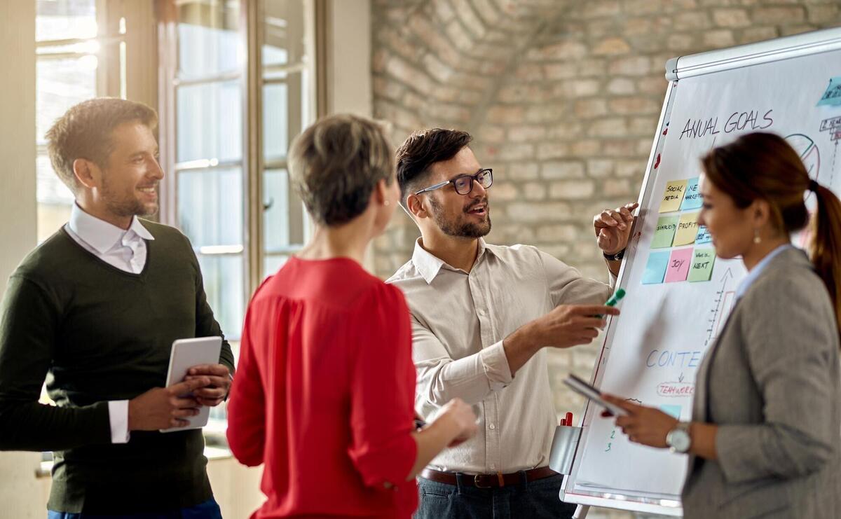 Business team cooperating while developing new business strategy in the office Focus is on young man presenting the ideas on whiteboard