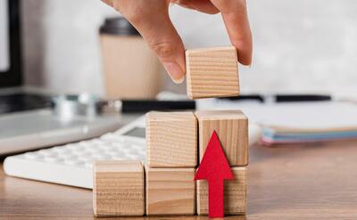 Hand placing wooden block to represent growth