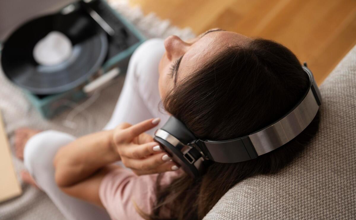 Woman listening to music through headphones at home