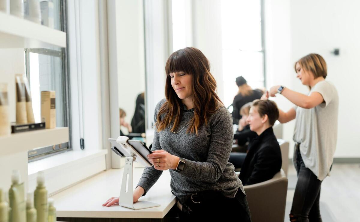 woman in gray sweater holding tablet computer