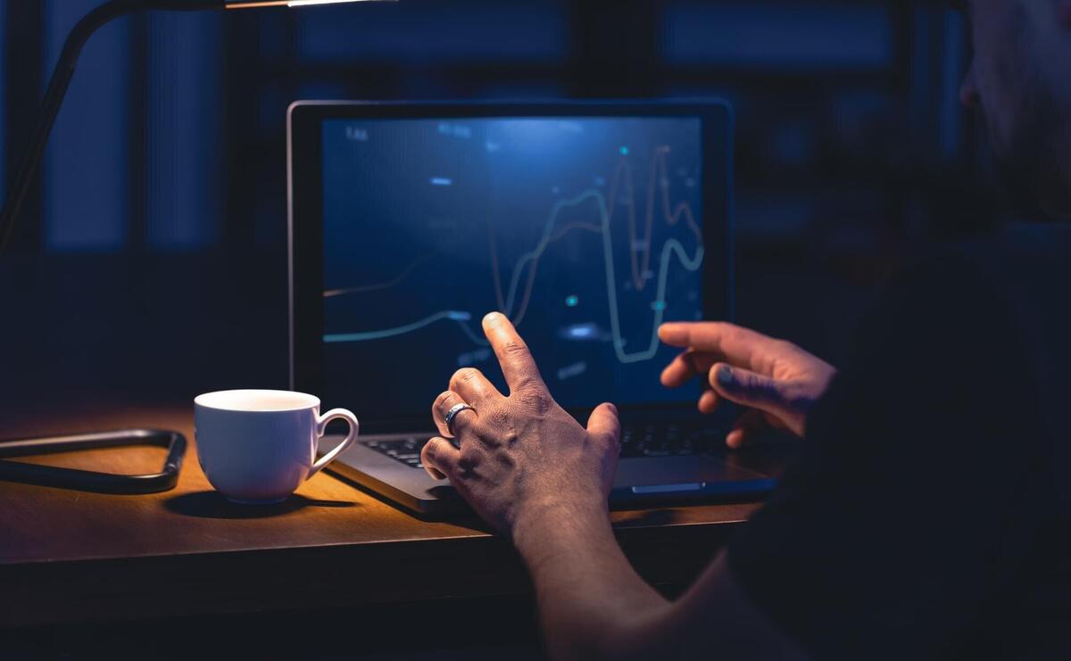 Man trading browsing online stock investments at night