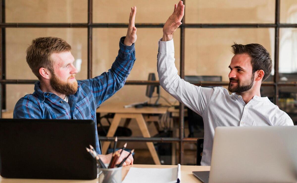 Two successful male colleague giving high five in office