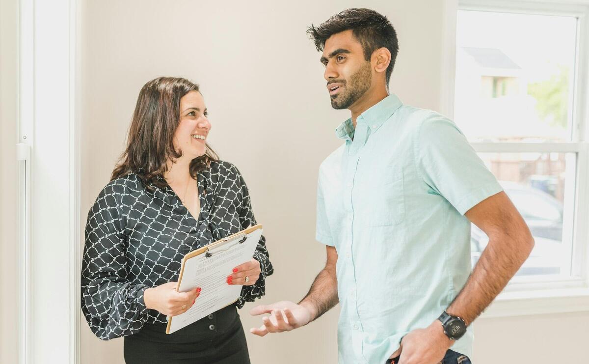 Real estate agent smiles while discussing property details with a client indoors.