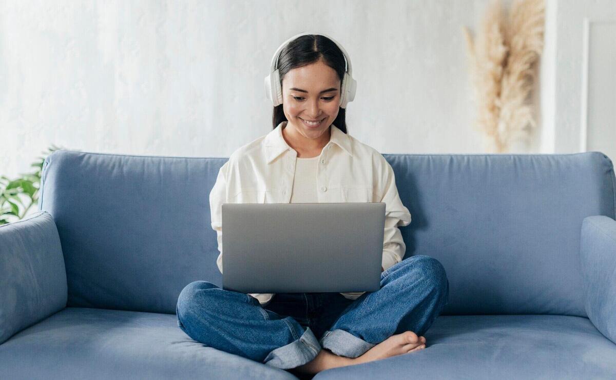 Smiley woman with headphones working on laptop