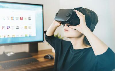 woman using black VR headset beside computer