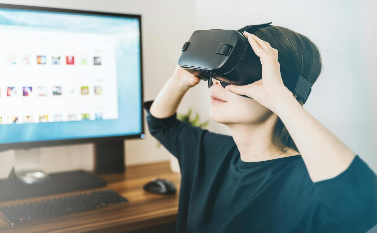 woman using black VR headset beside computer