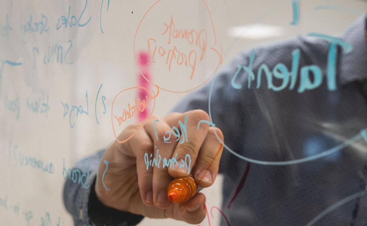 Person is writing on a transparent whiteboard.