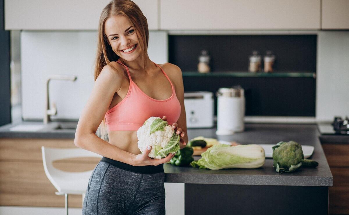 Young sporty woman with cauliflower at the kitchen