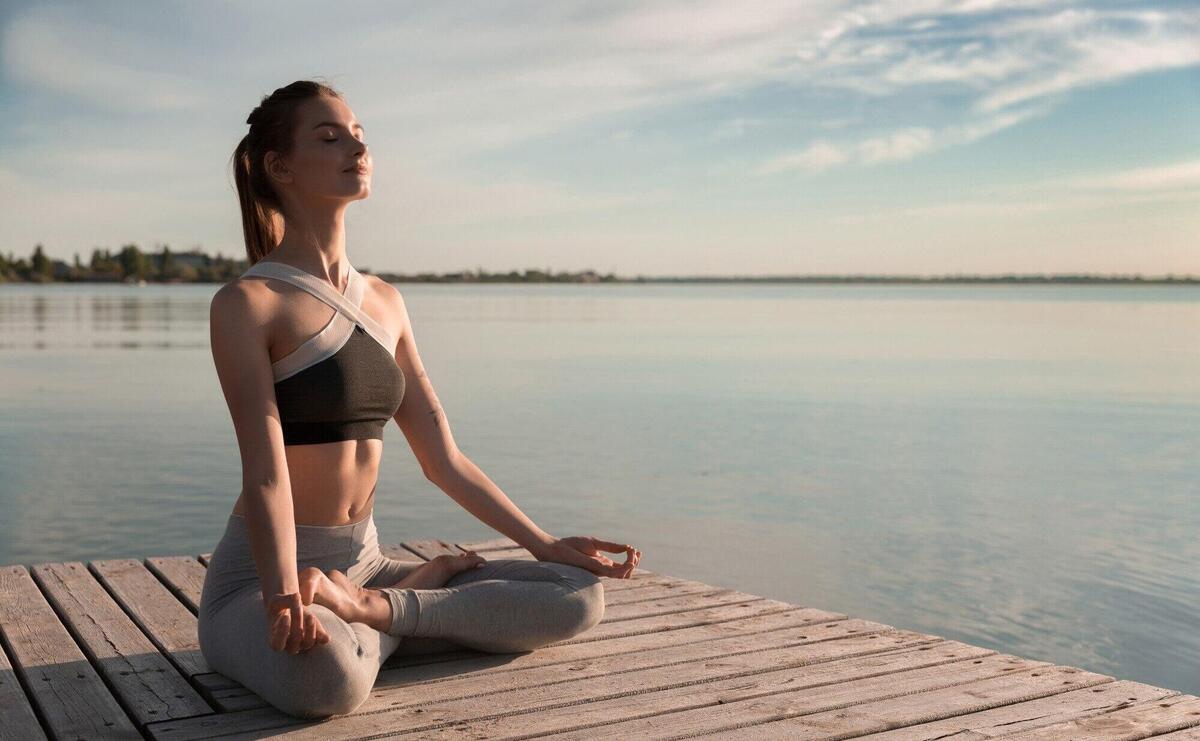 Young sports lady at the beach make meditation exercises.