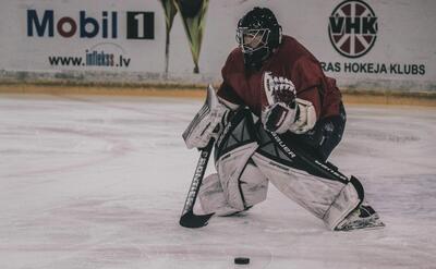 ice hockey player on court playing near mobil 1 and VHK painted wall