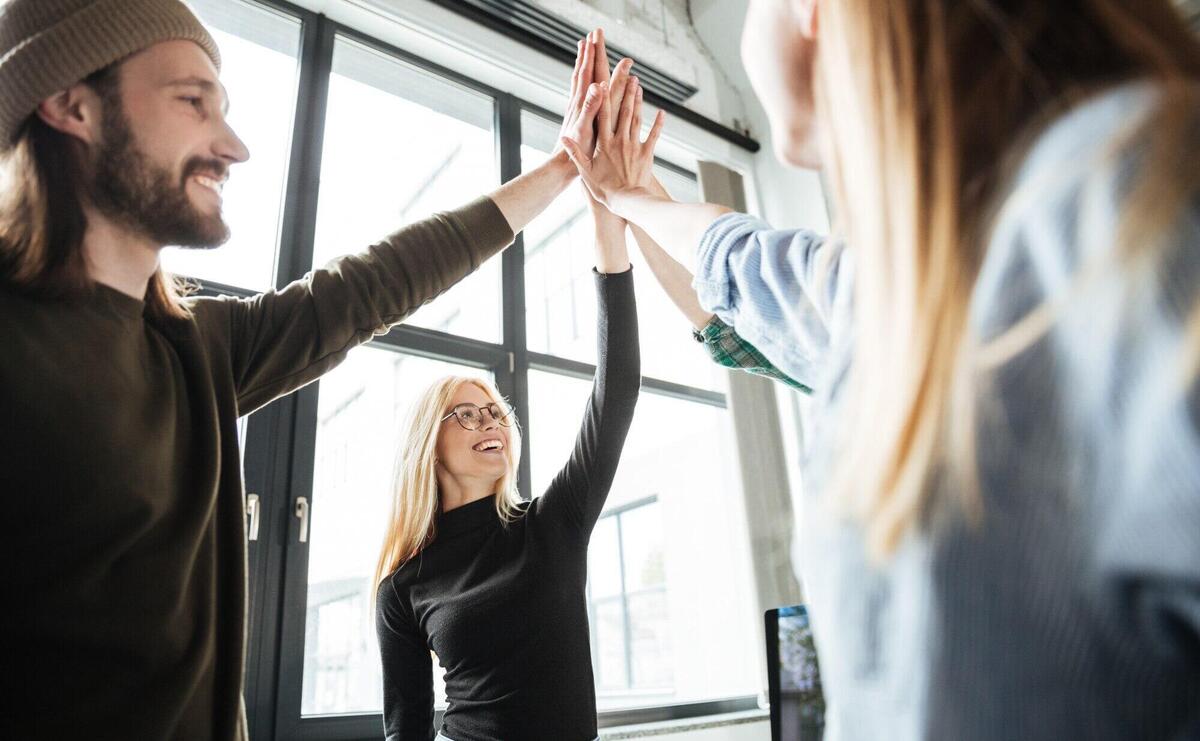 Happy colleagues in office give high five to each other