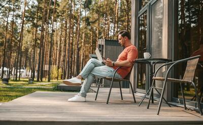 Work from home. A young man with a laptop sitting outside and working online