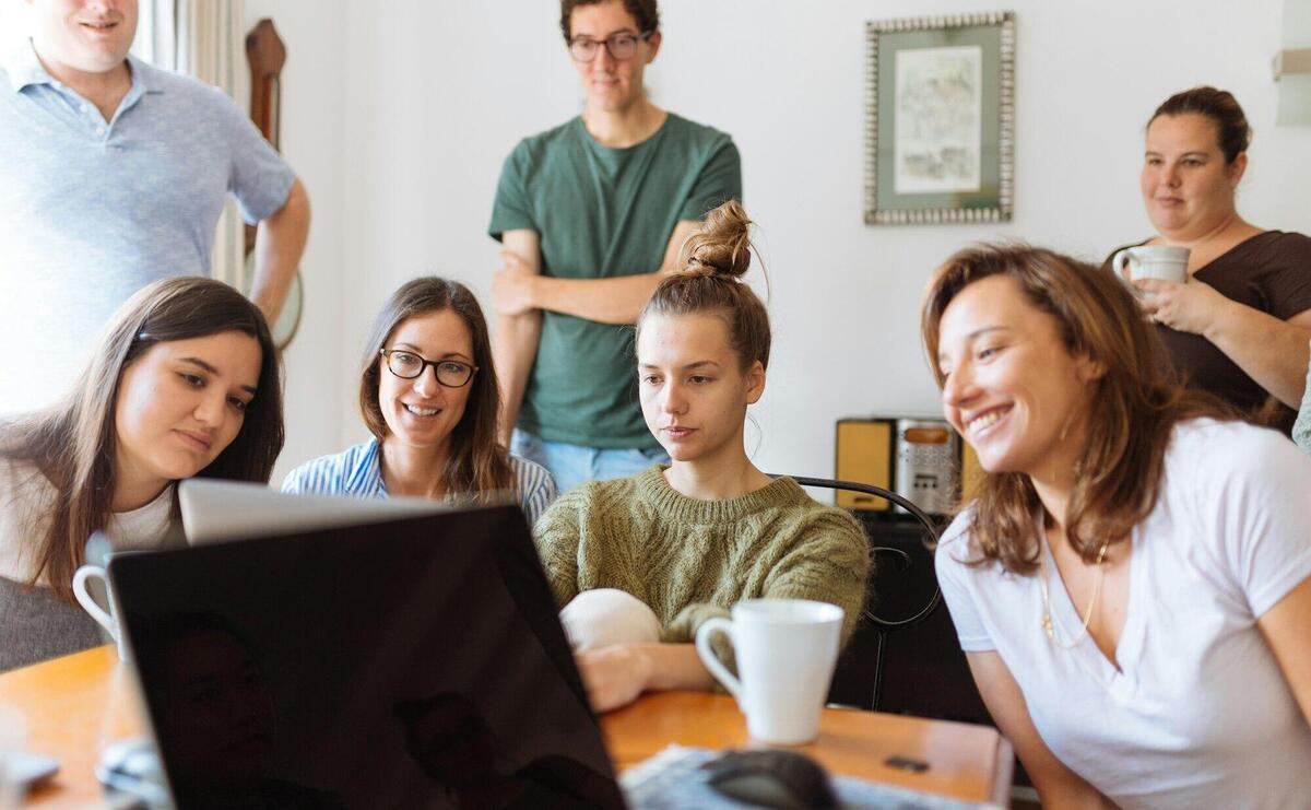 A diverse group of adults at work, enjoying a casual meeting indoors with focus and smiles.