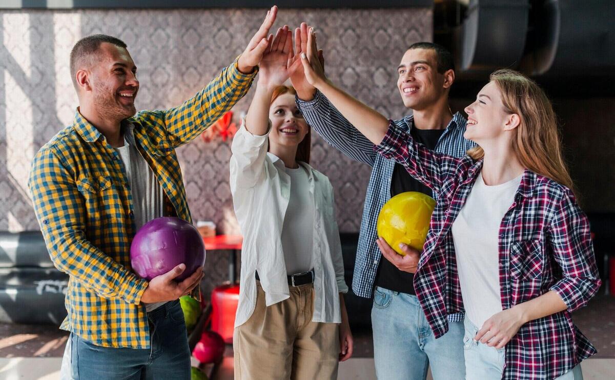 Happy friends with bowling balls in a bowling club