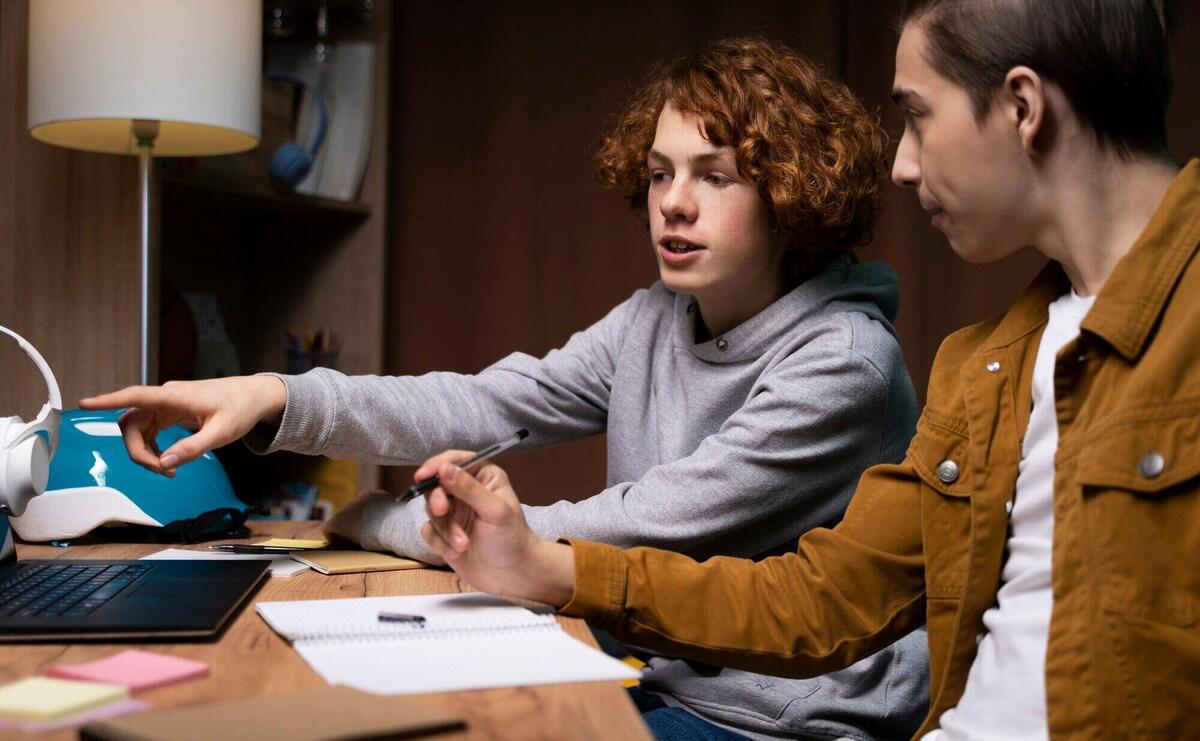 Two teenage boys studying together at home with laptop