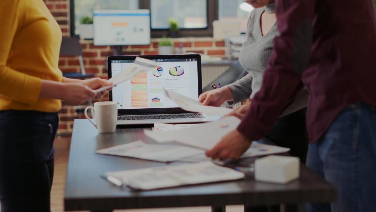 Business people looking at project reports on files to plan successful presentation with financial charts and results. Man and women working together to help with company growth. Close up