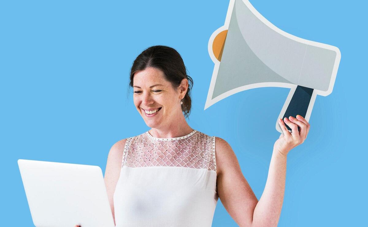 Woman holding a megaphone icon and using a laptop