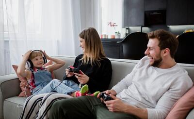 Laughing parents with controllers looking at daughter