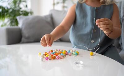 Adorable little girl making accessories with different colorful balls