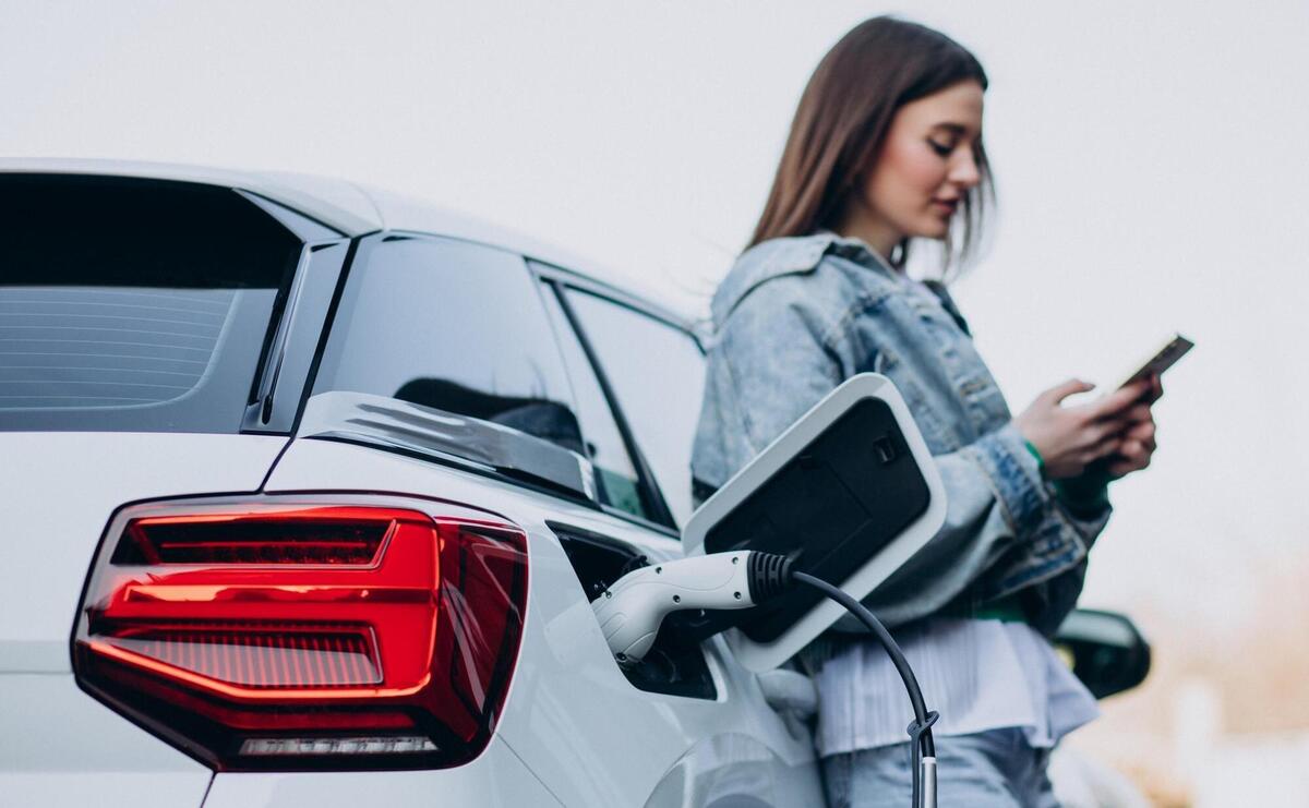 Woman charging her electric car with charging pistol