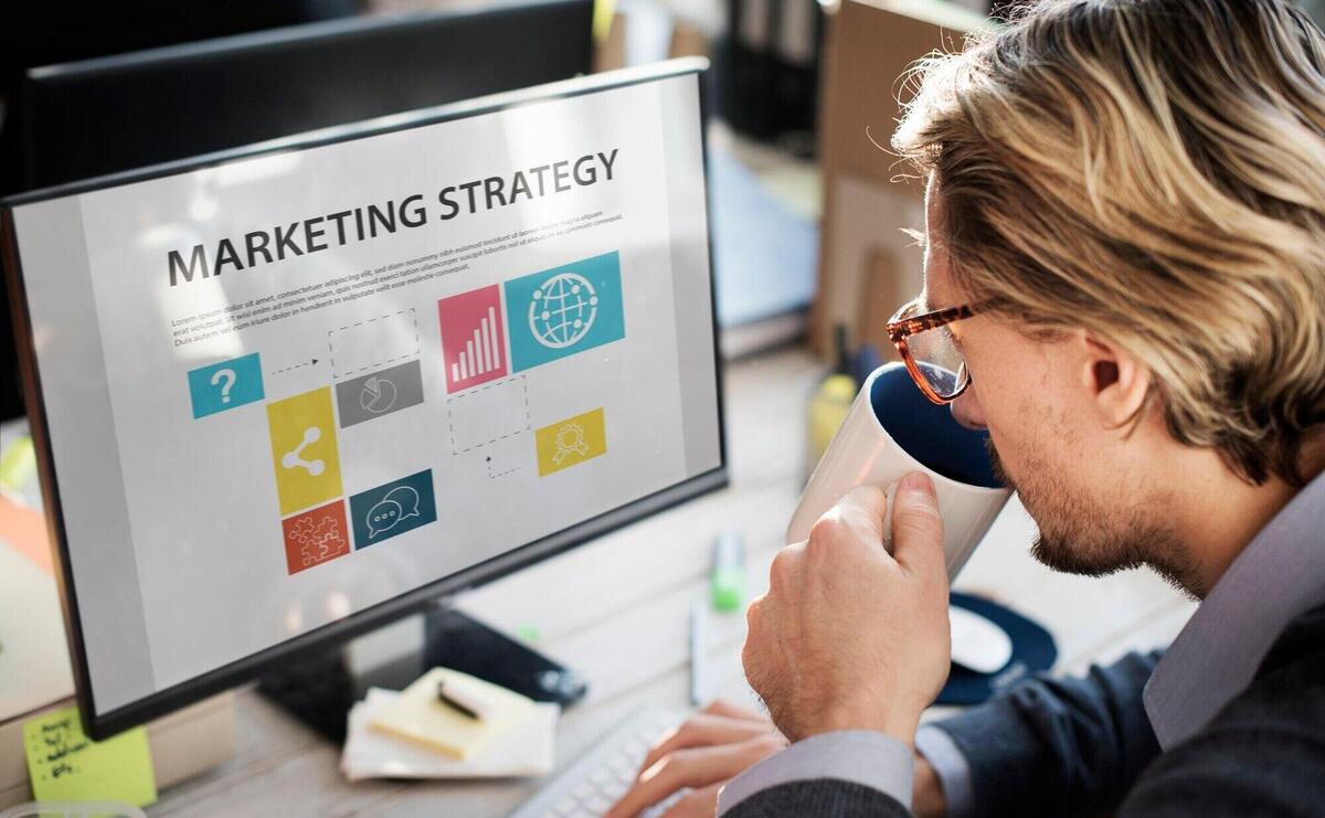 Closeup of caucasian man drinking coffee with computer screen showing marketing strategy