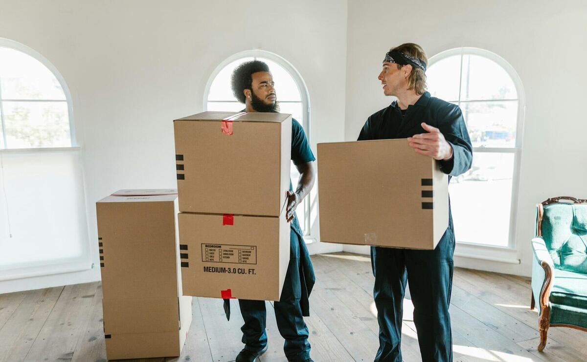 Men Carrying Cardboard Boxes while Having a Conversation